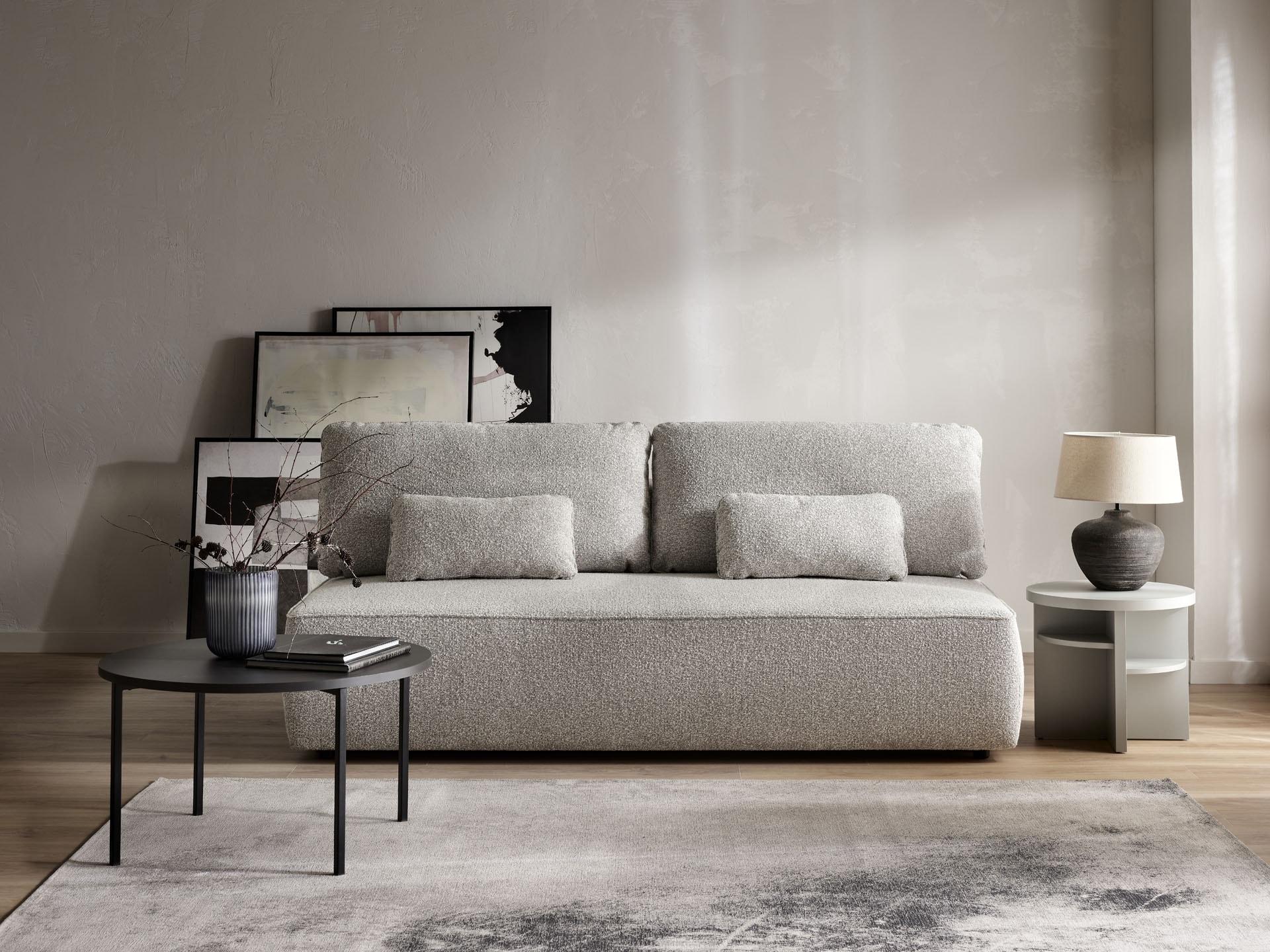 Niewielka szara sofa na tle beżowej ściany