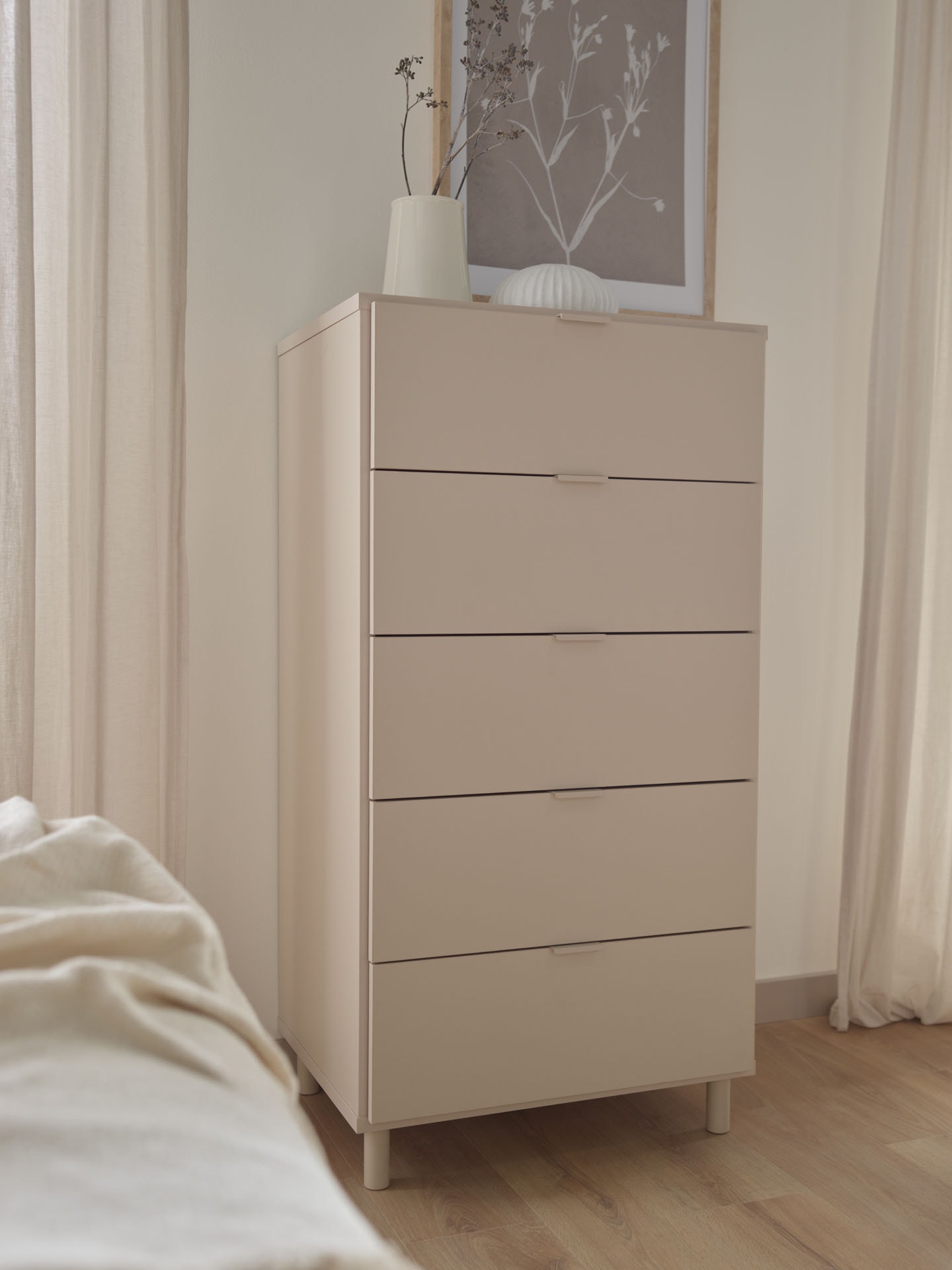 Wysoka komoda z szufladami na tle jasnej ściany