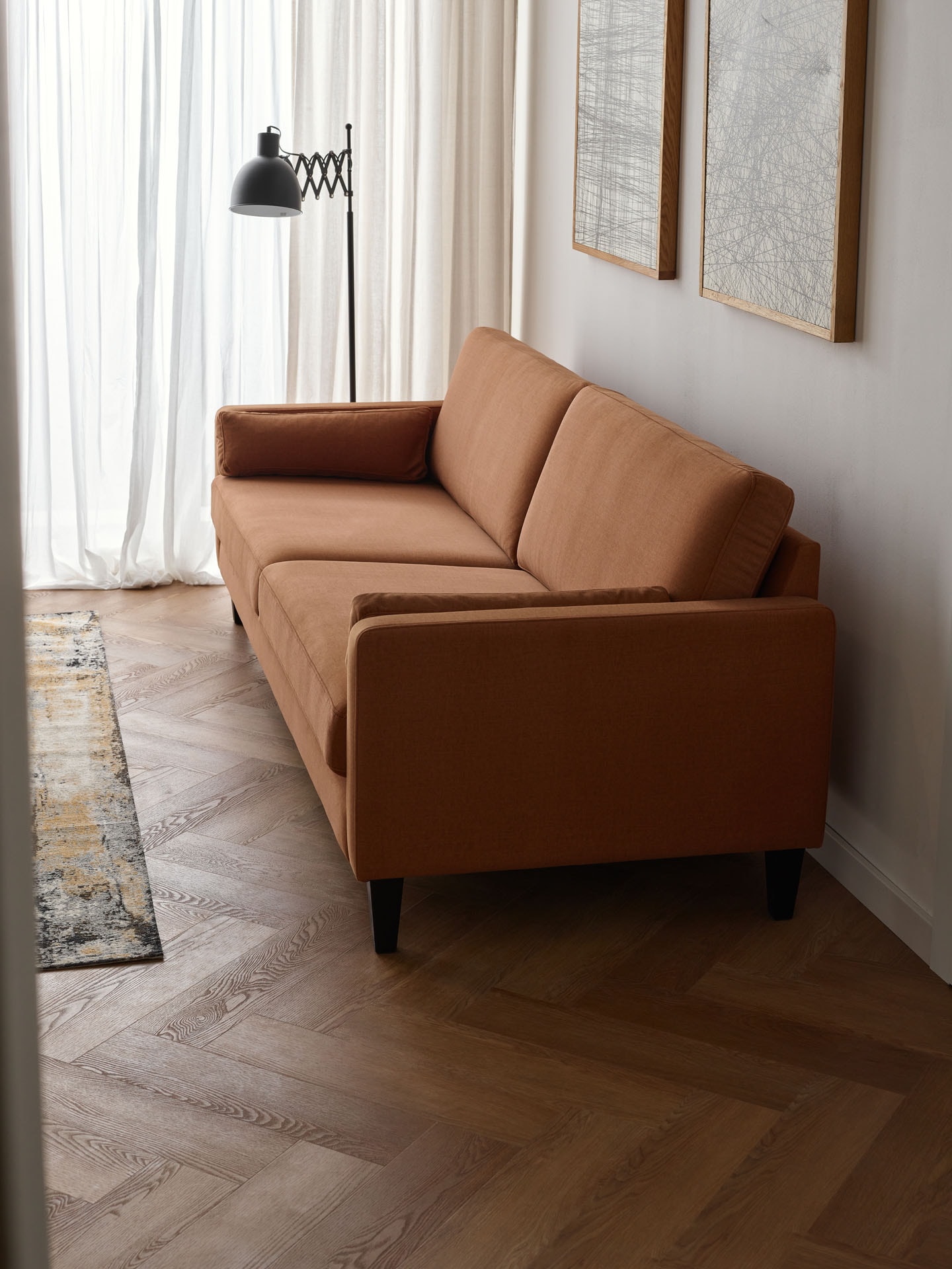  Ruda sofa na tle beżowej ściany