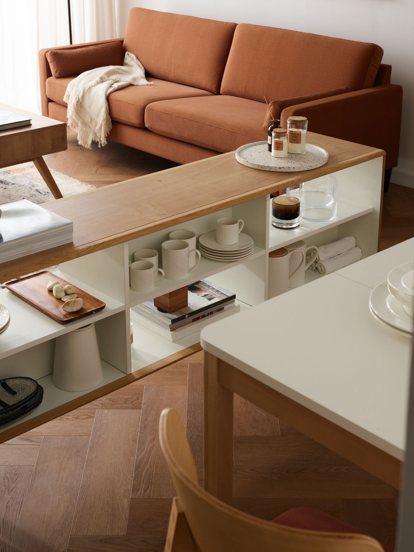 Ruda sofa, komoda w kolorze drewna na tle beżowej ściany
