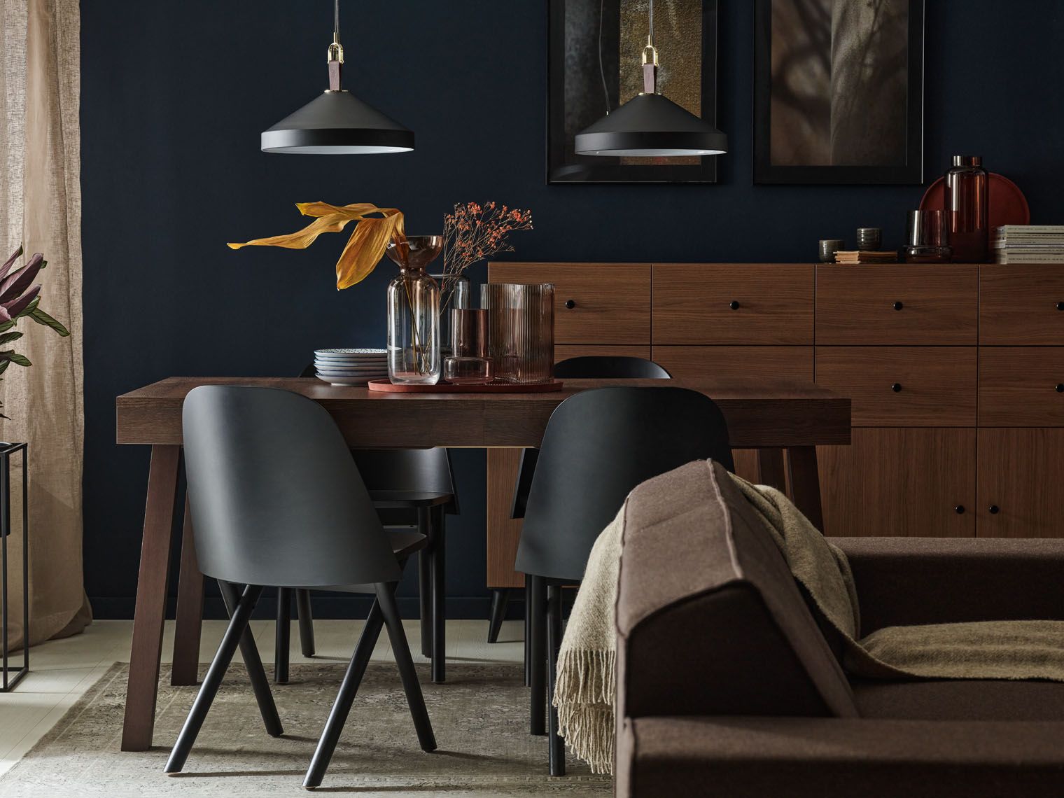 Elegancka jadalnia z ciemnymi brązowymi meblami i granatową ścianą.