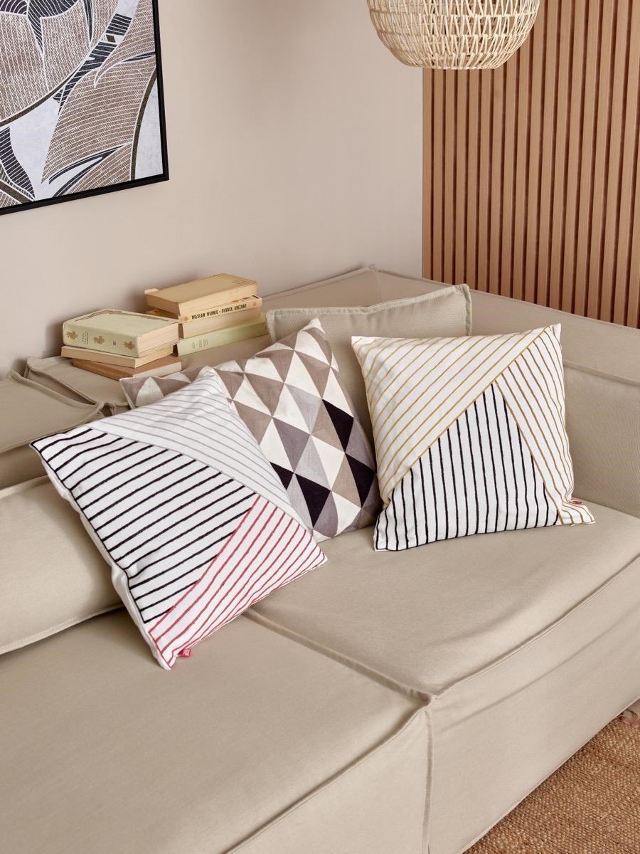 Beżowa sofa z dekoracyjnymi poduszkami w geometryczne wzory.