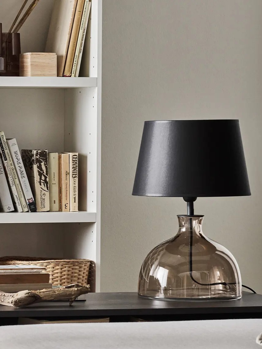 Elegancka lampa stołowa z czarnym abażurem i szklaną podstawą w stylu glamour.
