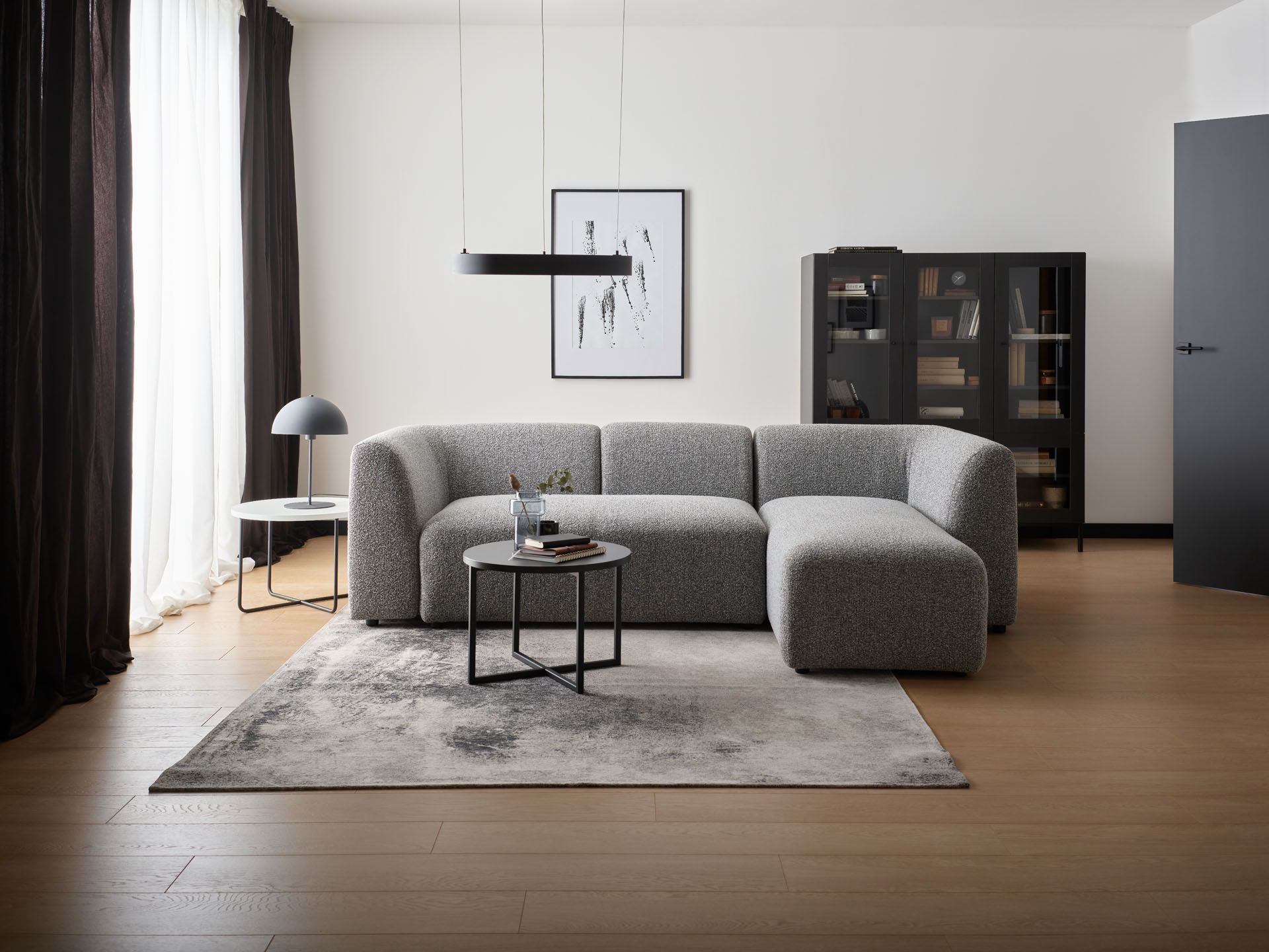Nowoczesna szara sofa w minimalistycznym salonie z czarnymi akcentami.