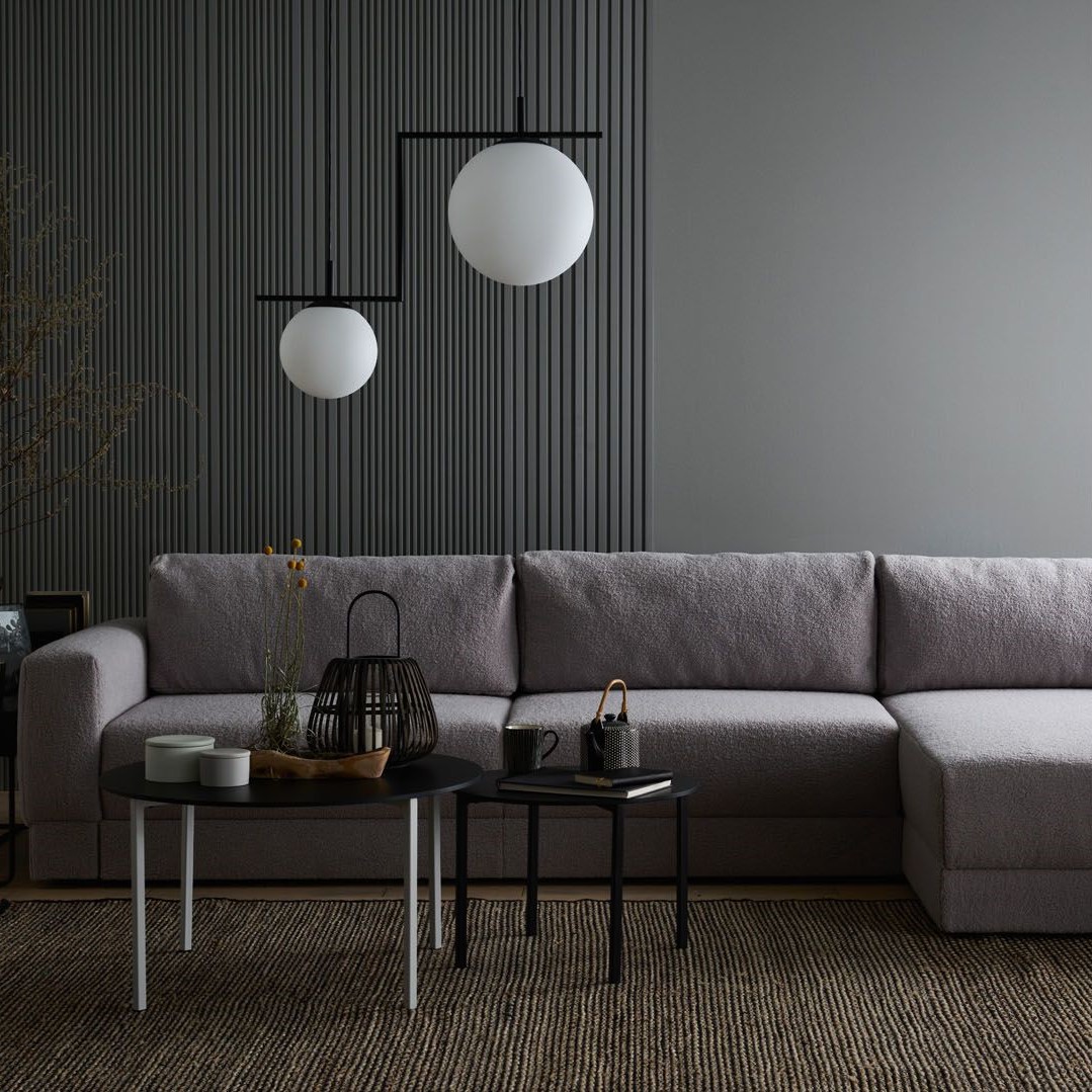 Minimalistyczna szara sofa w eleganckim, ciemnym wnętrzu.