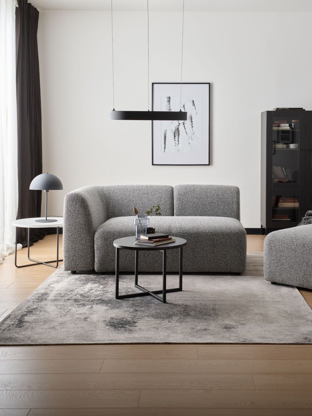 Nowoczesna szara sofa w minimalistycznym wnętrzu z czarnymi akcentami.