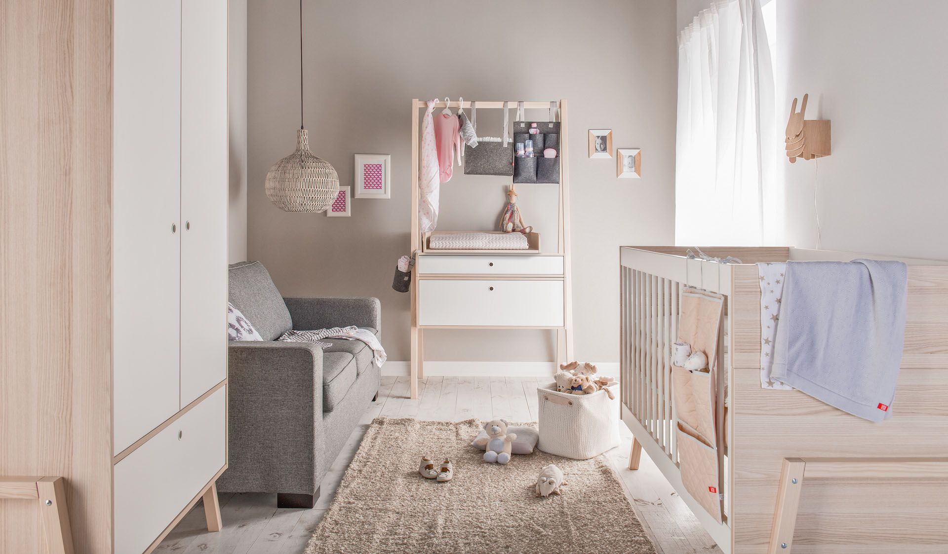 Łóżeczko niemowlęce w stylu boho, z naturalnymi dodatkami i jasną kolorystyką.