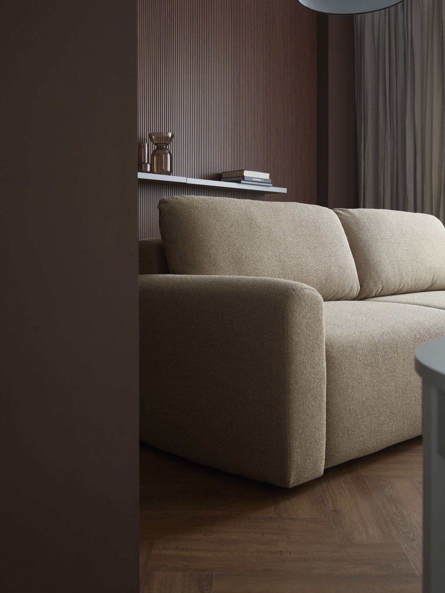 Różne kolory mebli w salonie – beżowa sofa na tle brązowej ściany