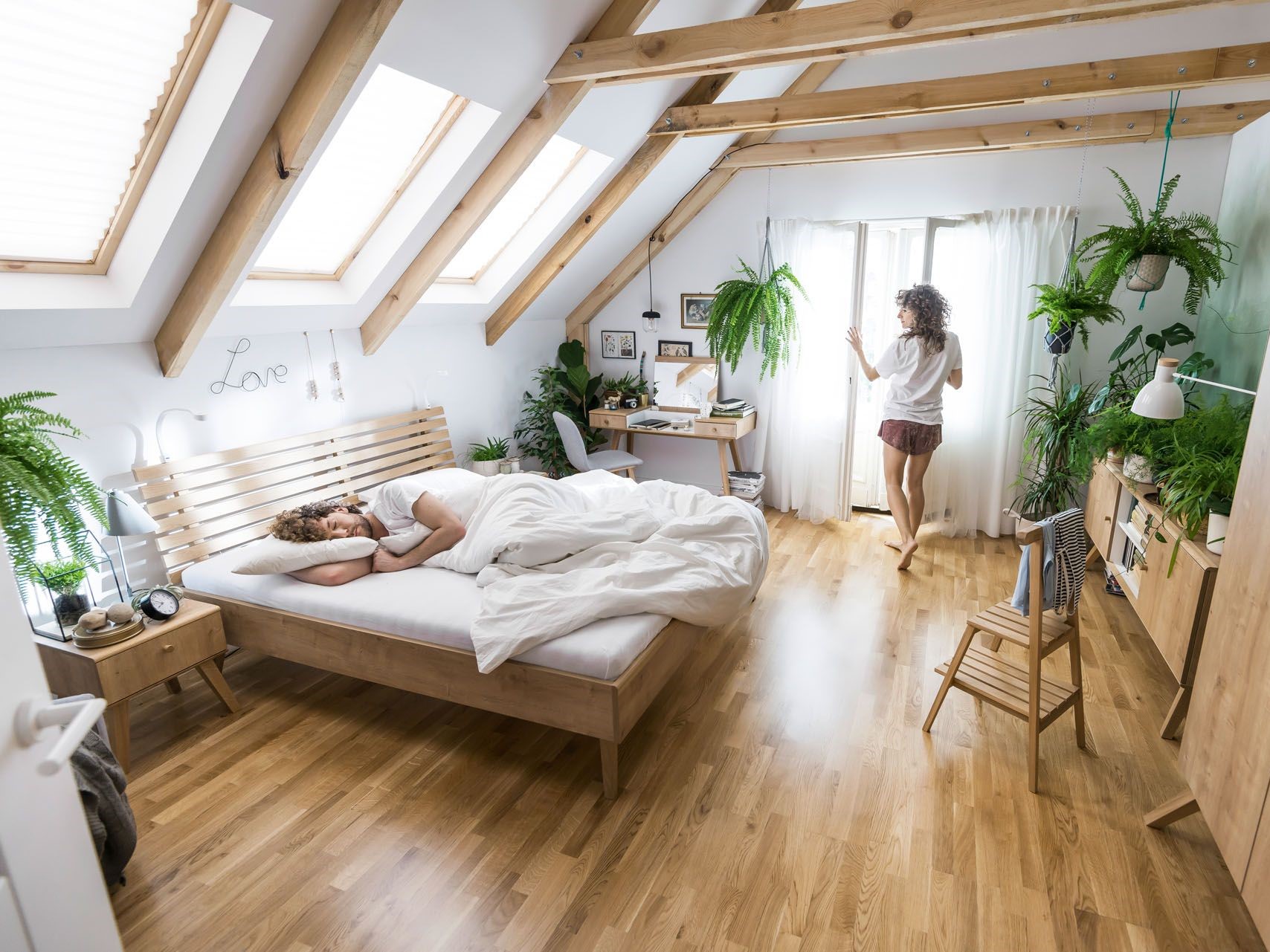 Sypialnia na poddaszu z dużą ilością naturalnego drewna i roślin