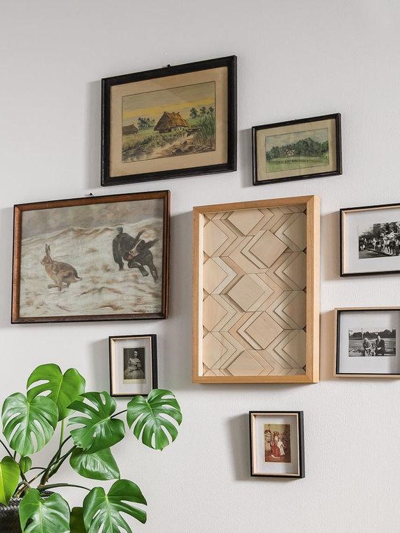 Galeria obrazów w stylu vintage z różnorodnymi ramami i klasycznymi grafikami.