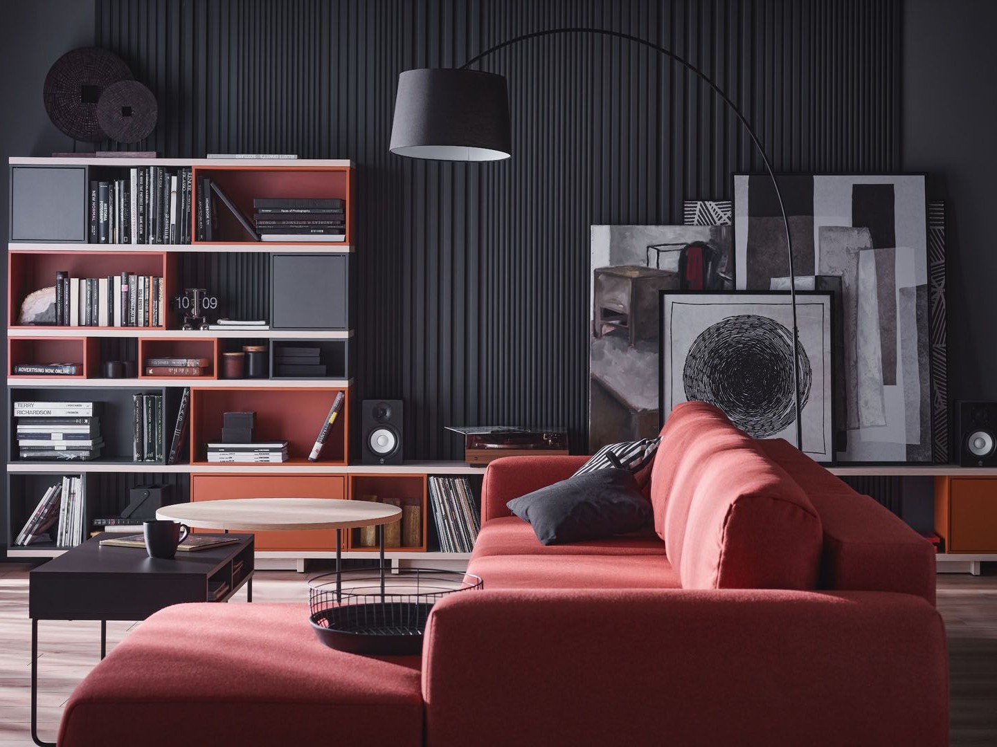 Salon z ceglastą sofą i czarną ścianą z półkami 