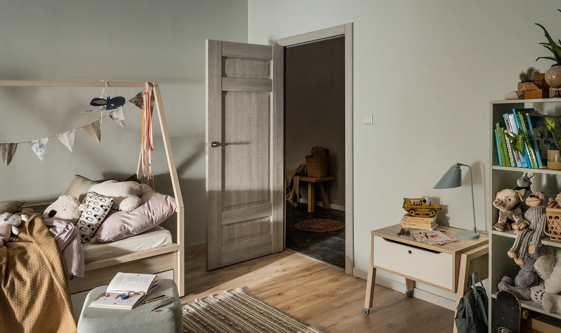 Drzwi wewnętrzne w przytulnym pokoju dziecięcym z naturalnymi meblami.