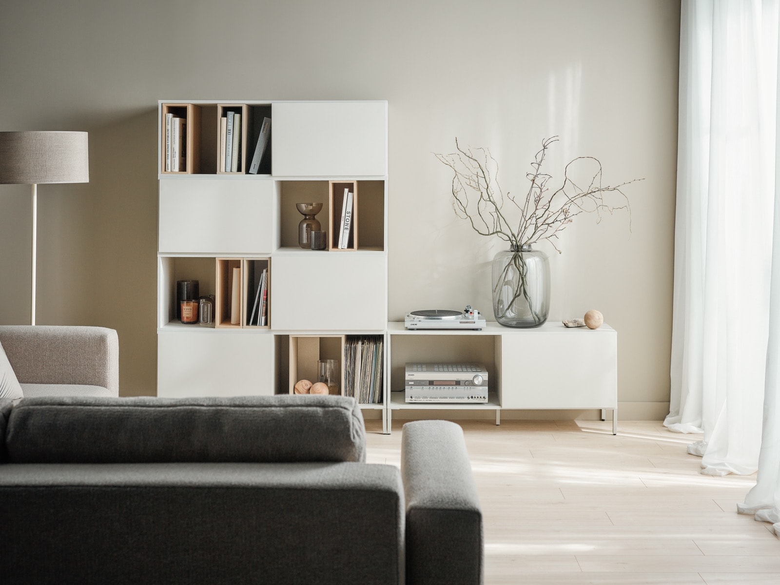  Salon w stylu minimalistycznym – regał Into na beżowej ścianie