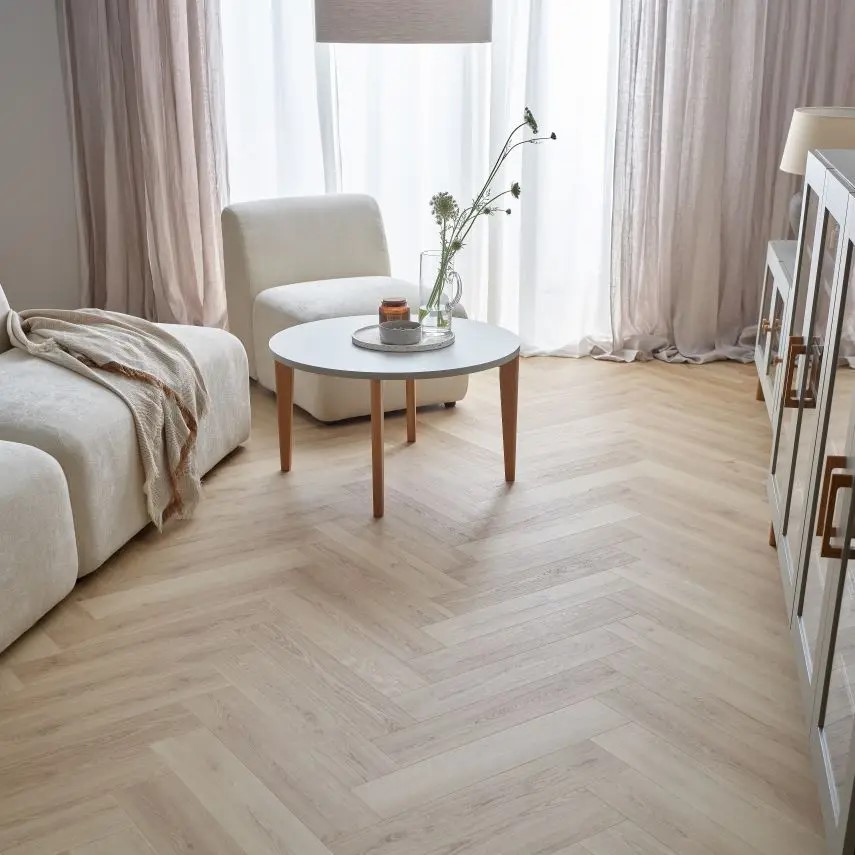 Jasny salon z podłogą w jodełkę i minimalistycznymi meblami.