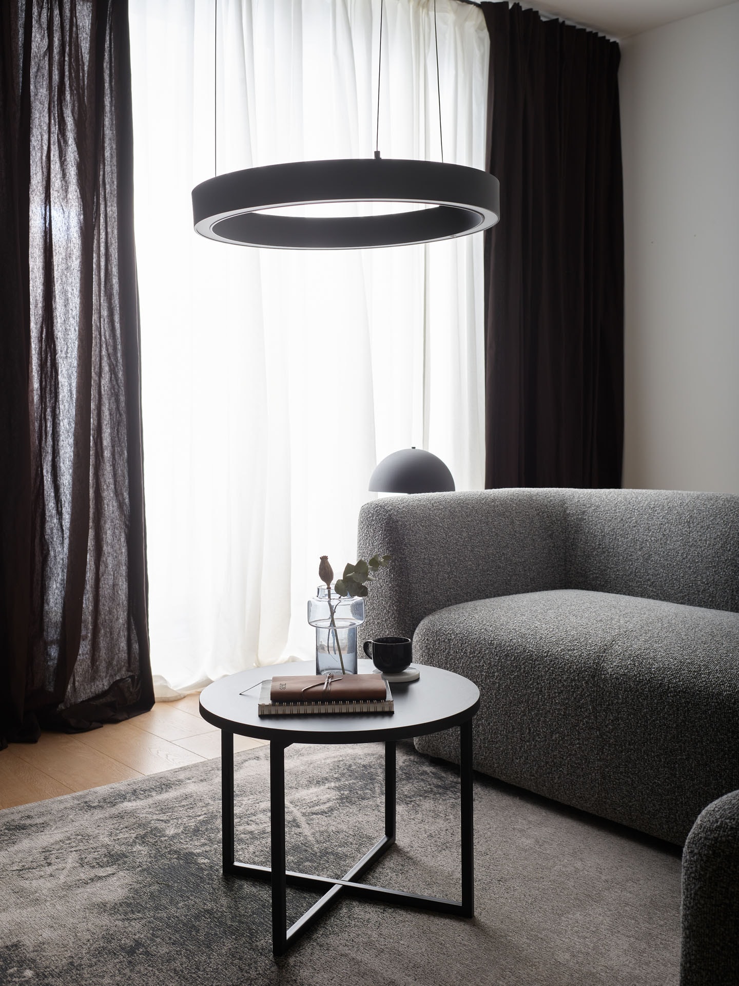 Szara sofa i okrągła lampa