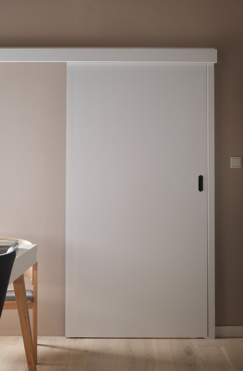 Proste białe drzwi przesuwne w minimalistycznym wnętrzu.