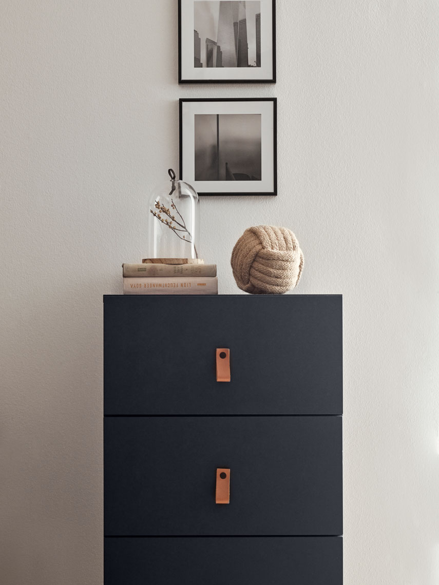 Ciemna komoda z minimalistycznymi uchwytami i dekoracjami 