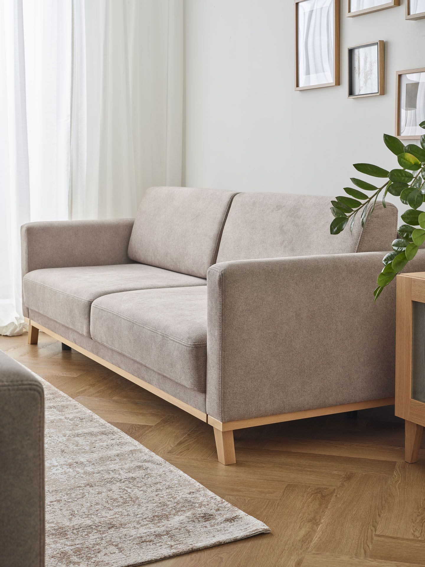 Minimalistyczny salon z beżową sofą na drewnianych nogach