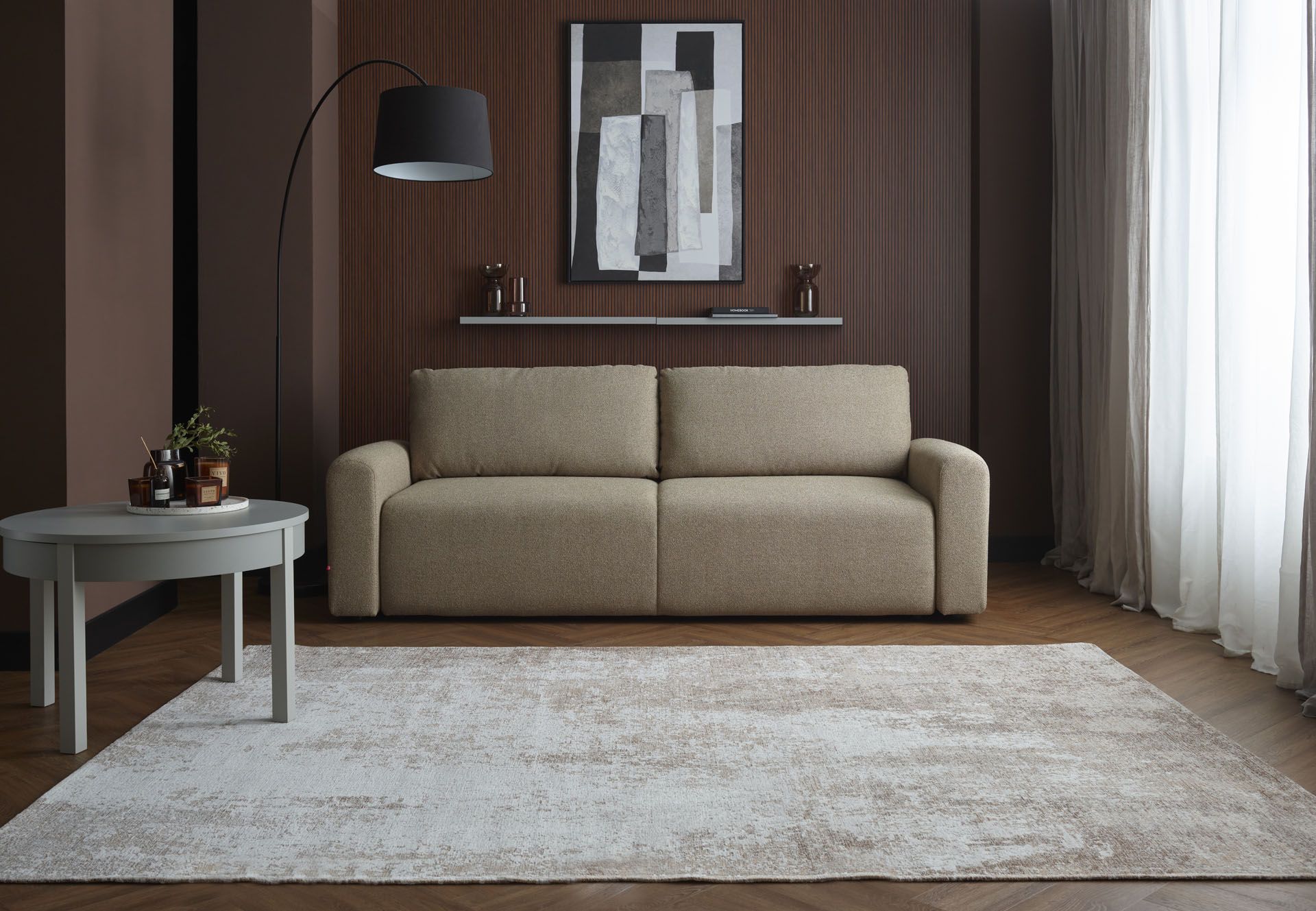 Beżowa sofa na tle brązowej ściany z lamelami.