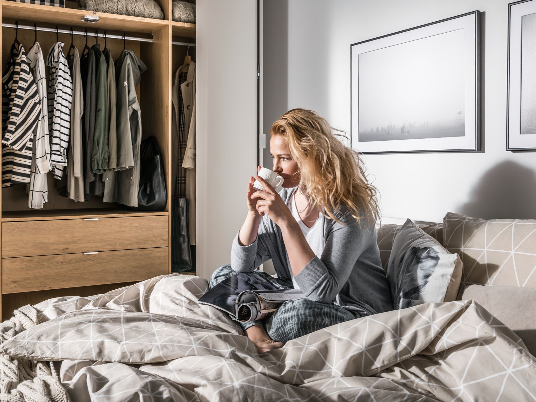 kobieta z kubkiem siedzi na łóżku w sypialni