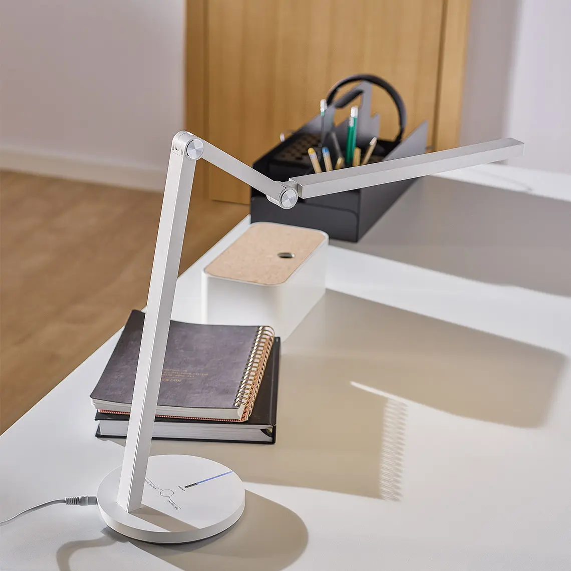 Minimalistyczna lampka biurkowa na białym blacie.