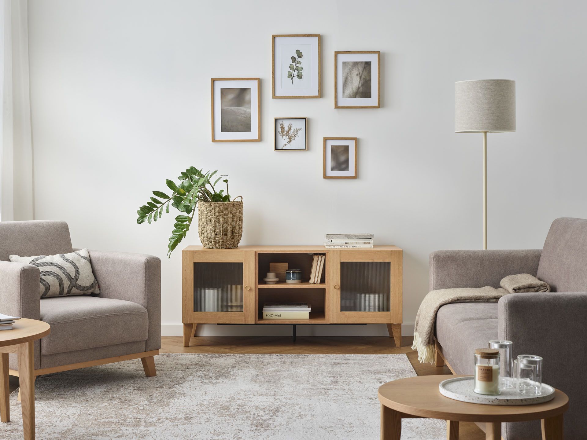 Salon z beżowymi fotelami, komodą i galerią ścienną