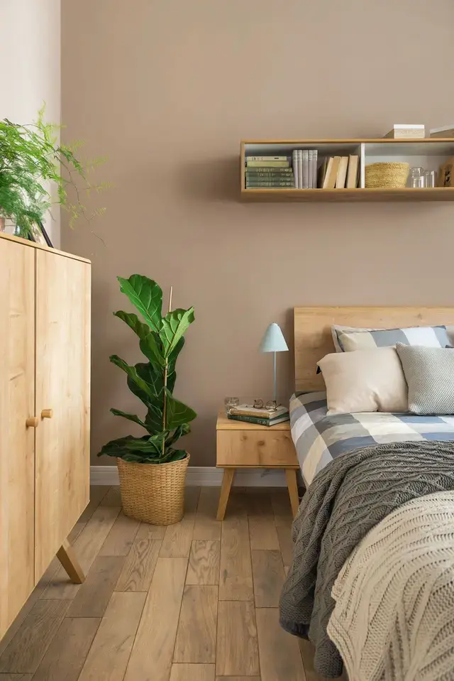 Sypialnia w stylu naturalnym z jasnym drewnem i dużą rośliną w koszu.