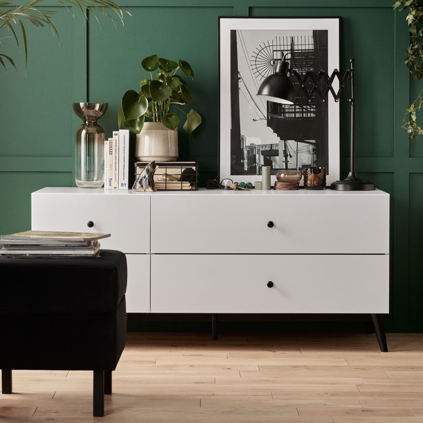 elegancki salon z zieloną boazerią i białą komodą 