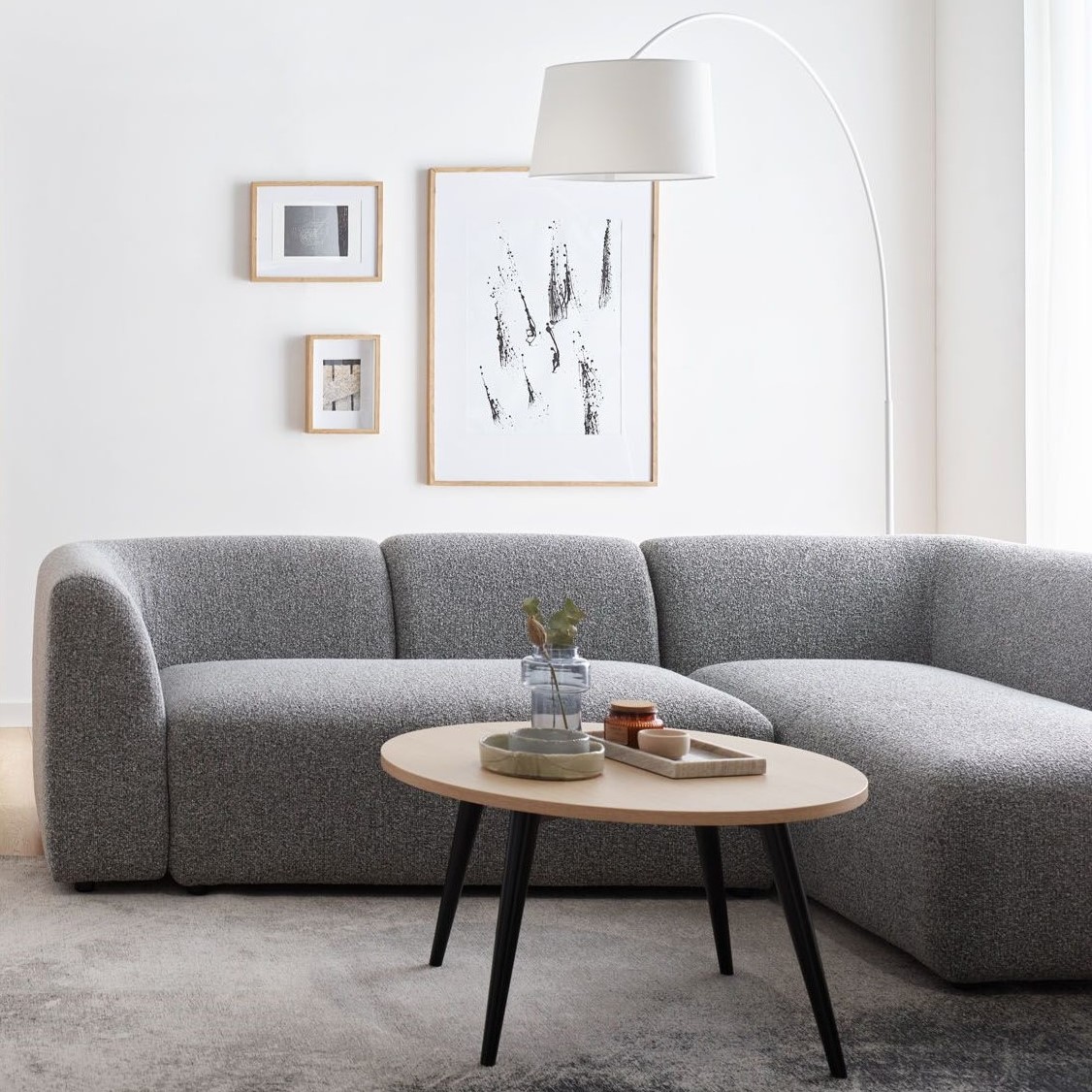 Minimalistyczny salon z szarą sofą i białymi ścianami.