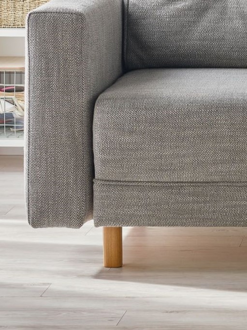 Szara tapicerowana sofa na drewnianych nóżkach