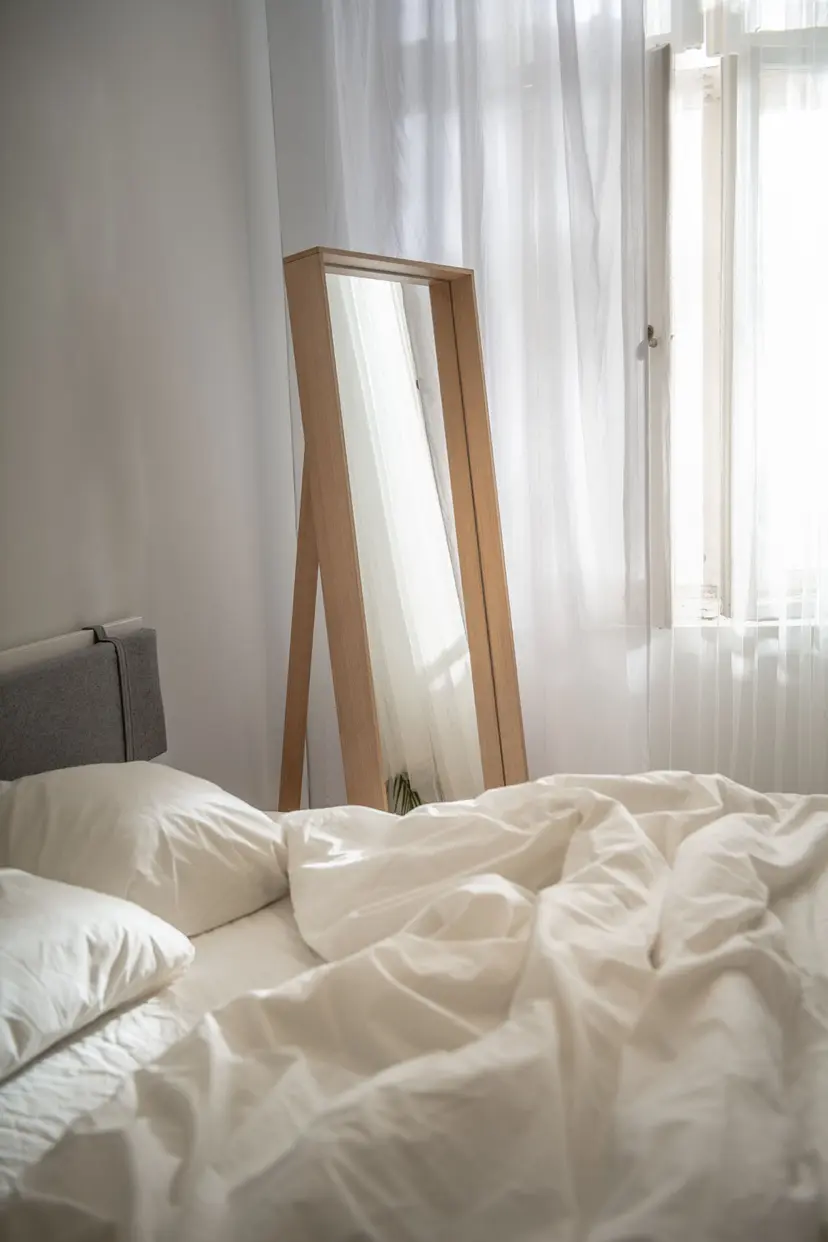 Lustro opierające się o ścianę w minimalistycznej sypialni.