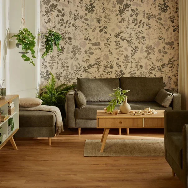 przytulny salon ze ścianą jest roślinnym motywem w którym znajduą się ciemnozielone meble wypoczynkowe i drewniany stolik kawowy.