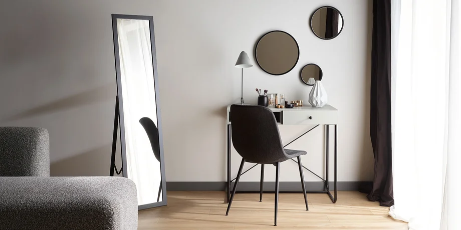 Minimalistyczna toaletka z okrągłymi lustrami i eleganckim krzesłem, tworząca stylową przestrzeń do codziennej pielęgnacji.